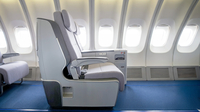 Auf dem Bild ist ein Flugzeugsitz in einem modernen Kabineninneren zu sehen.