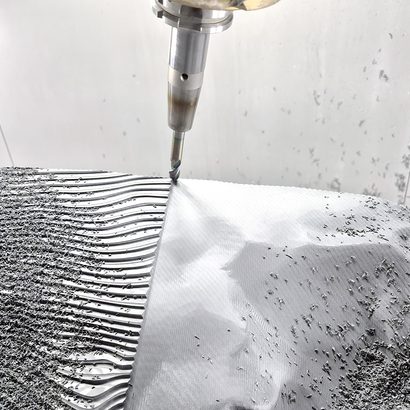 Auf dem Bild ist ein Bearbeitungsprozess mit einer Fräse zu sehen, bei dem Metallspäne entstehen.