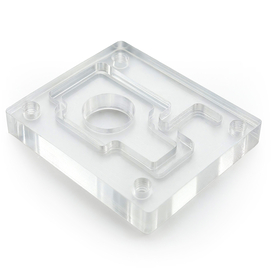 Auf dem Bild ist ein transparenter, klarer Kunststoffblock mit einer bearbeiteten Form und mehreren Gewindebohrungen zu sehen.