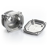 Auf dem Bild sind zwei Metallteile zu sehen, die vermutlich Teile eines Motors sind, darunter ein Gehäuse mit Kühlrippen und eine Abdeckung.